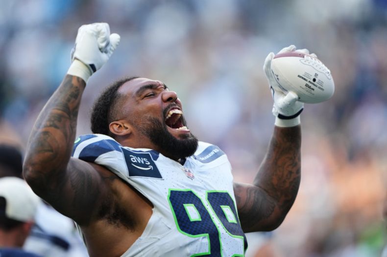 El tackle defensivo de los Seahawks de Seattle Leonard Williams reacciona hacia los aficionados mientras lanza un balón autografiado a los asistentes durante el campamento de entrenamiento el sábado 8 de agosto del 2026. (AP Foto/Lindsey Wasson)