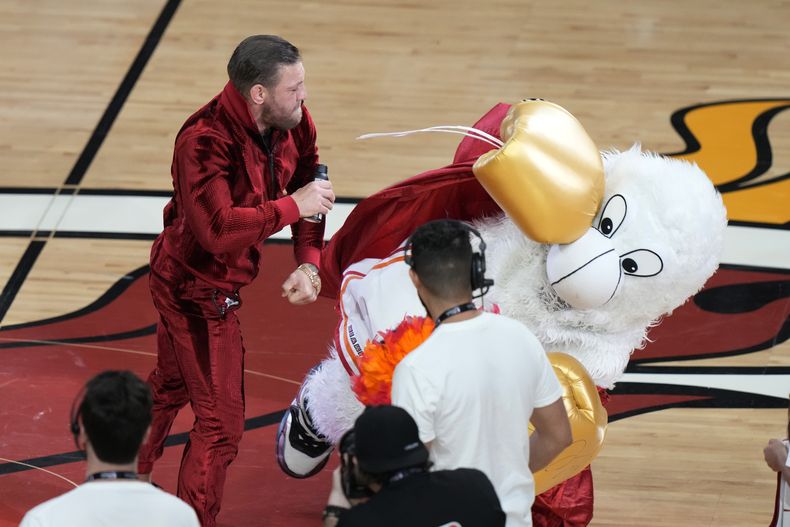 El excombatiente de artes marciales mixtas Conor McGregor propina un puñetazo a Burnie, mascota del Heat de Miami, durante una pausa en el cuarto partido de las Finales de la NBA ante los Nuggets de Denver, el viernes 9 de junio de 2023 (AP Foto/Lynne Sladky)