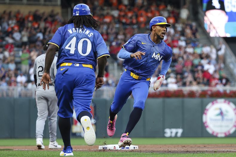 Byron Buxton, derecha, de los Mellizos de Minnesota, dobla en tercera base con un doble del bateador designado Royce Lewis durante la tercera entrada del juego de béisbol en contra de los Medias Blancas de Chicago, el viernes 2 de agosto de 2024, en Minneapolis. Buxton anotó en la jugada. (AP Foto/Matt Krohn)