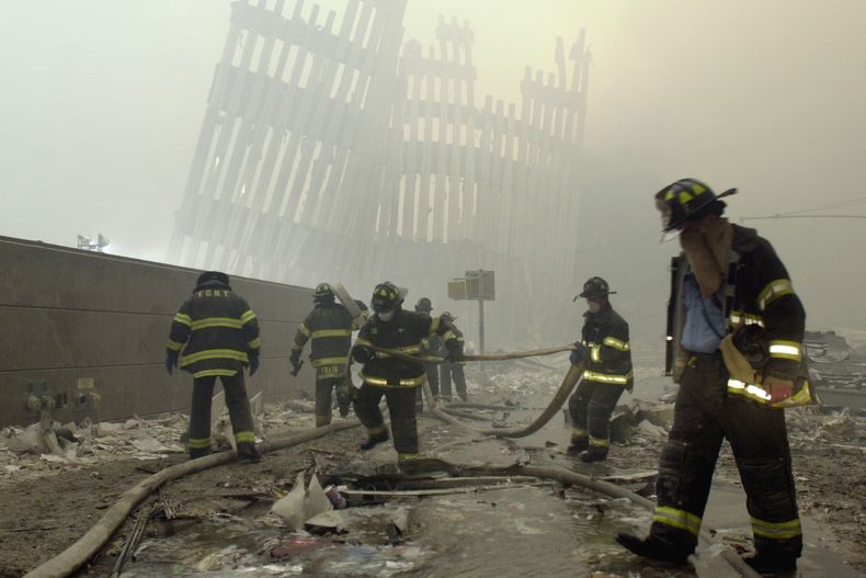 ARCHIVO - En esta foto del 11 de septiembre de 2001, los bomberos trabajan bajo los parteluces destruidos, los puntales verticales que en su día sostenían los muros exteriores de las torres del World Trade Center, tras un ataque terrorista contra las torres gemelas en Nueva York.. (AP foto/Mark Lennihan, archivo)