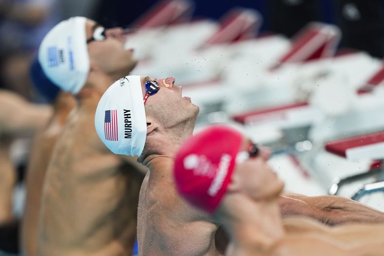 Nadadores se preparan para la largada de la prueba de los 100 metros espalda de los Juegos Olímpicos de París, domingo 28 de julio de 2024, en Nanterre, Francia. (AP Foto/Martín Meissner)