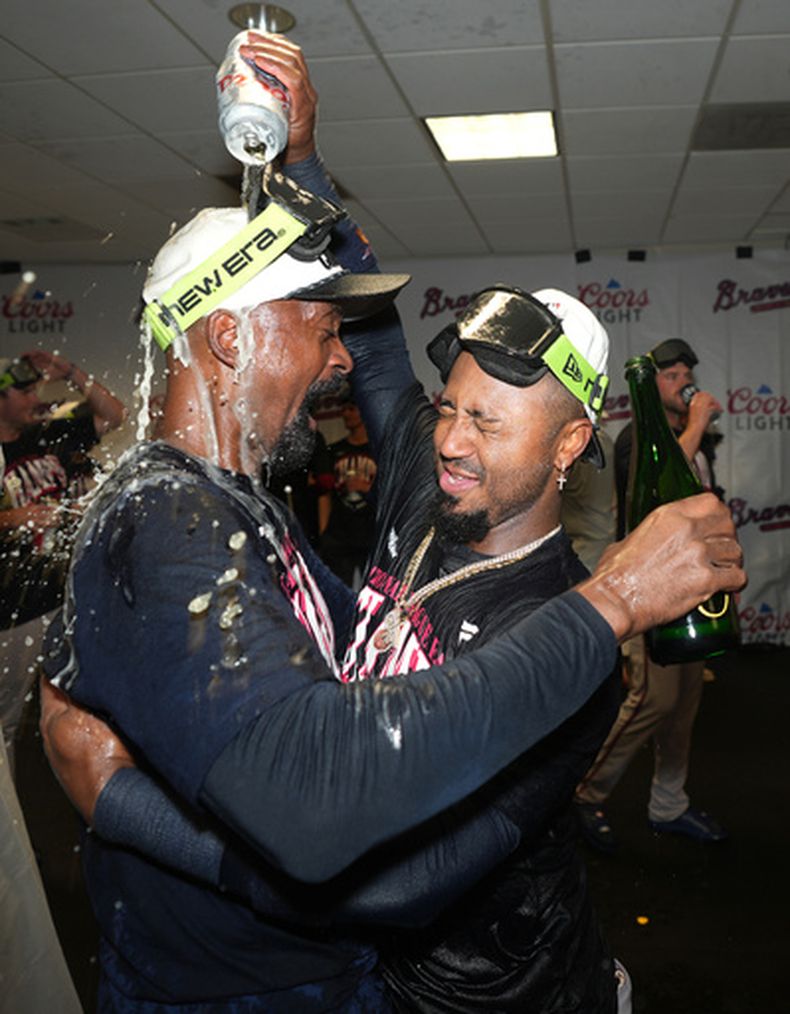 Ozzie Albies, derecha, de los Bravos de Atlanta, celebra en la casa club del equipo visitante con el coach de bateo Darnell Coles, izquierda, después de la victoria sobre los Astros de Houston, con la que los Bravos aseguraron el título del Este de la Liga Americana, el domingo 20 de septiembre de 2026, en Houston. (AP Foto/Karen Warren)