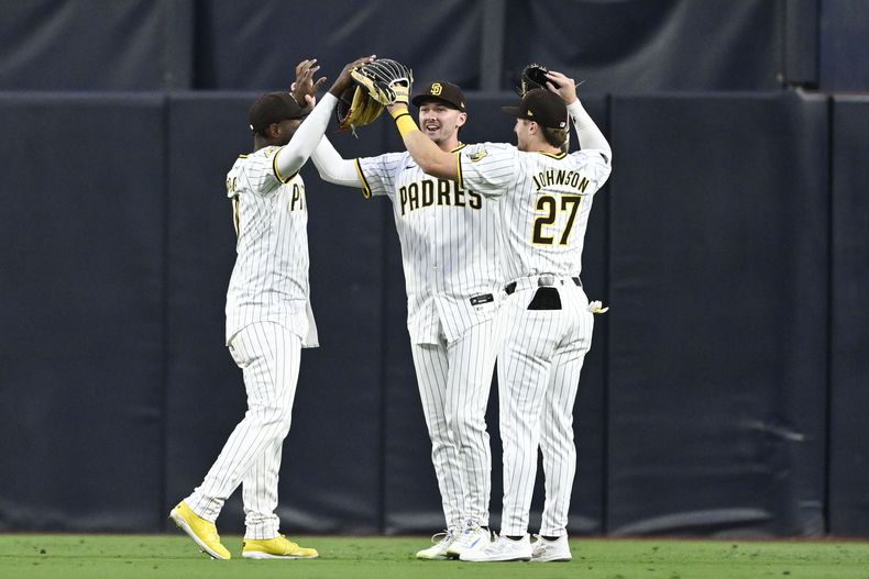 El jardinero izquierdo de los Padres de San Diego, Jurickson Profar, a la izquierda, Jackson Merrill, al centro, y Bryce Johnson, a la derecha, celebran después de derrotar a los Rockies de Colorado el sábado 3 de agosto de 2024, en San Diego. (AP Foto/Denis Poroy)