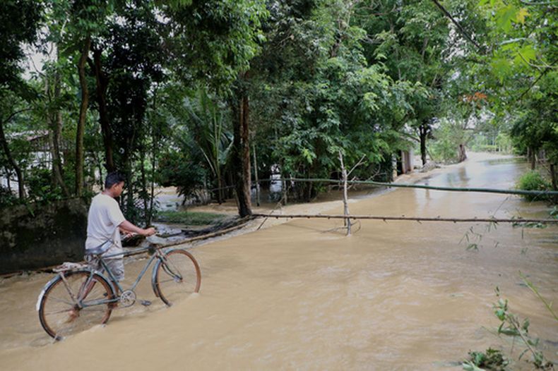 Un hombre circula en bicicleta por la localidad anegada de Teok, en Assam, India, el 24 de julio de 2026. (AP Foto/Parikhit Saikia)