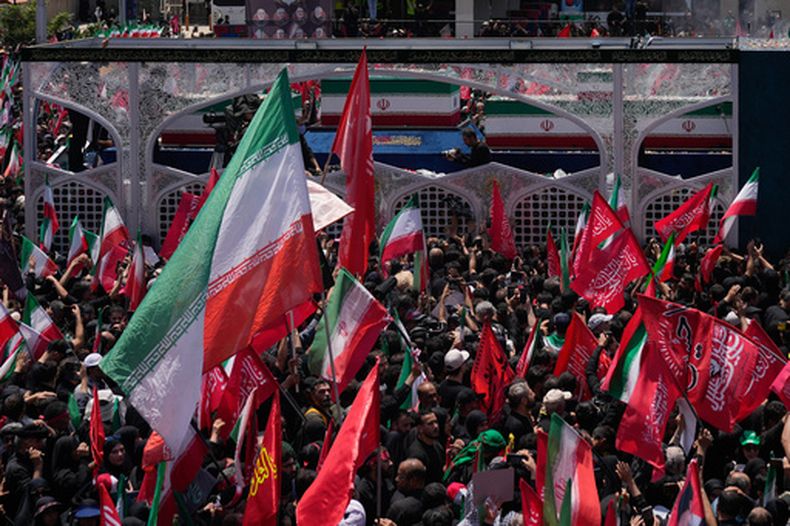 Un camión, en la parte superior, que transporta los ataúdes del difunto líder supremo iraní, el ayatolá Alí Jamenei, y miembros de su familia, avanza entre los dolientes durante su procesión fúnebre, el lunes 6 de julio de 2026, en Teherán, Irán. (AP Foto/Altaf Qadri)