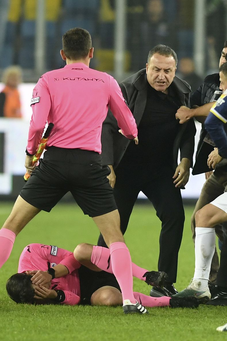 El árbitro Halil Umut Meler se toca el rostro mientras yace tendido en el césped tras ser golpeado por el presidente del MKE Ankaragucu, Faruk Koca (centro derecha), al final del partido de la Super Liga turca entre el MKE Ankaragucu y el Caykur Rizespor en Ankara, el 11 de diciembre de 2023. (Abdurrahman Antakyali/Depo Photos vía AP)