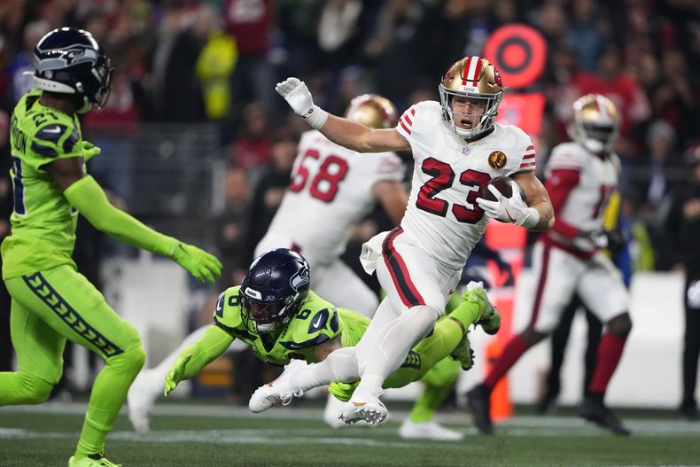 Christian McCaffrey (23), running back de 49ers de San Francisco, se escapa del safety Quandre Diggs (6), de los Seahawks de Seattle, durante la primera mitad del juego de la NFL, el jueves 23 de noviembre de 2023, en Seattle. (AP Foto/Lindsey Wasson)