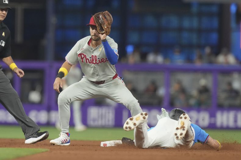 El campocorto de los Filis de Filadelfia, Trea Turner, trata de sacar a Troy Johnston, de los Marlins de Miami, roba la segunda base durante la sexta entrada de un juego de béisbol el domingo 7 de septiembre de 2025, en Miami. (AP Photo/Marta Lavandier)