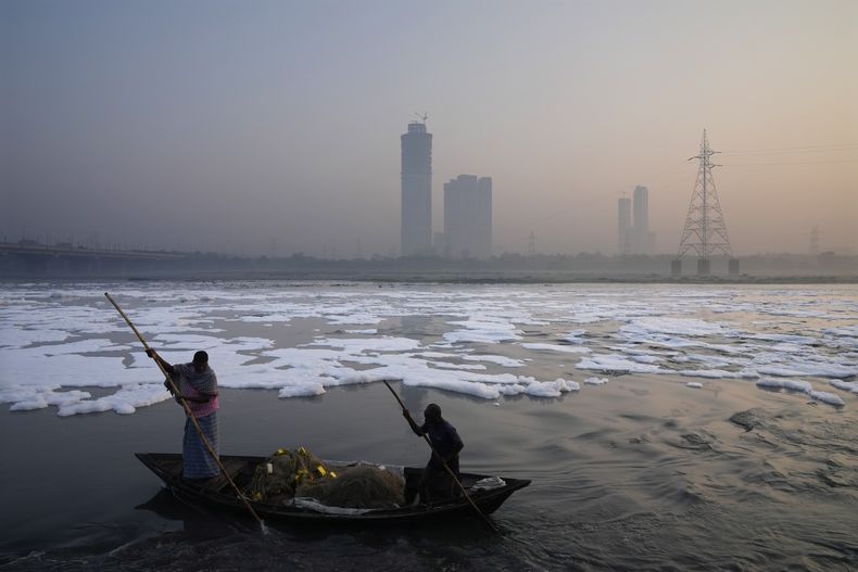 Pescadores reman en un bote entre el smog de la mañana en el río Yamnua, mientras espuma tóxica flota en el río antes del festival de Diwali en Nueva Delhi, India, el martes 29 de octubre de 2024. (AP Foto/Manish Swarup)
