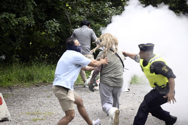 Una mujer rocía con un extinguidor a un Corán en llamas frente a la embajada iraní en Estocolmo, Suecia, viernes 18 de agosto de 2023. (Fredrik Sandberg/TT News Agency via AP)