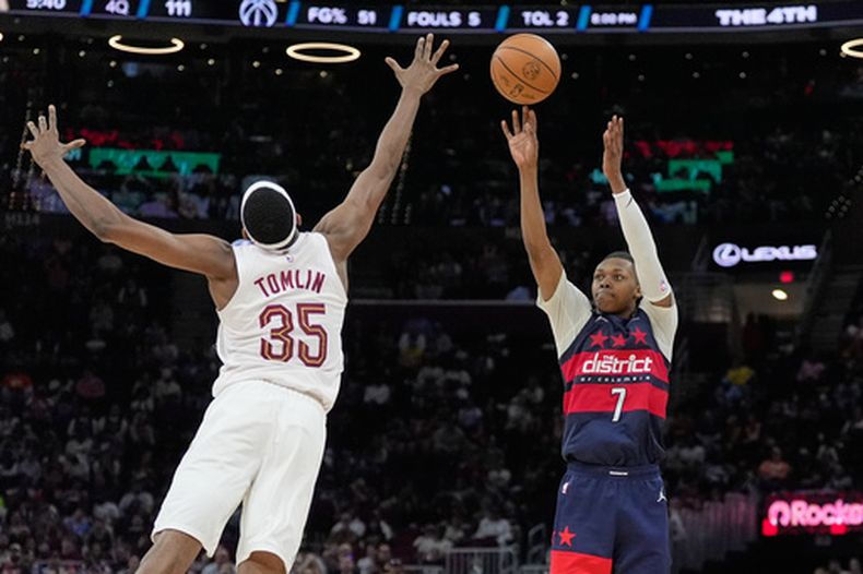 Bub Carrington (7), de los Wizards de Washington, dispara de larga distancia mientras Naeqwan Tomlin (35), de los Cavaliers de Cleveland, defiende en la segunda mitad del juego de baloncesto de la NBA, el domingo 12 de abril de 2026, en Cleveland. (AP Foto/Sue Ogrocki)