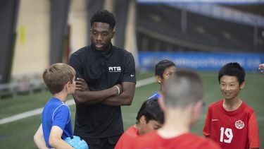 Alphonso Davies, de la selección canadiense, habla con niños durante un campamento en Edmonton, el martes 6 de junio de 2023 (Jason Franson/The Canadian Press via AP)