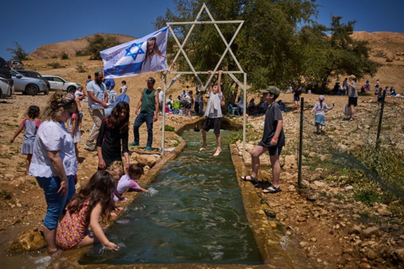 Un niño se cuelga en una estructura metálica con forma de estrella de David sobre un manantial en Auja, en el valle del Jordán, durante el Día de la Independencia de Israel, el 22 de abril de 2026, en la Cisjordania ocupada. (AP Foto/Ohad Zwigenberg)