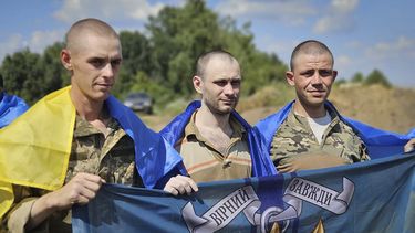En esta foto, proporcionada el miércoles 17 de julio de 2024 por la Oficina de Prensa de la Presidencia de Ucrania, prisioneros de guerra ucranianos sostienen banderas de la Marina mientras posan para una foto tras un intercambio de prisioneros en un lugar no revelado de Ucrania. (Oficina de Prensa de la Presidencia de Ucrania vía AP)