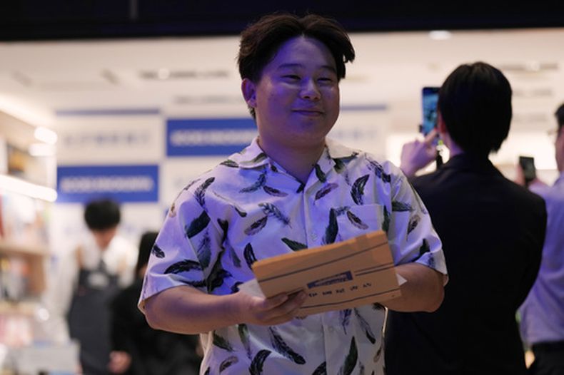 Atsushi Watanabe, un estudiante universitario de Hadano, al suroeste de Tokio, recibe un ejemplar del nuevo libro de Haruki Murakami, titulado La historia de Kaho, minutos después de la medianoche durante un evento de cuenta regresiva en una librería Kinokuniya de Tokio, el viernes 3 de julio de 2026. (Foto AP/Hiro Komae)