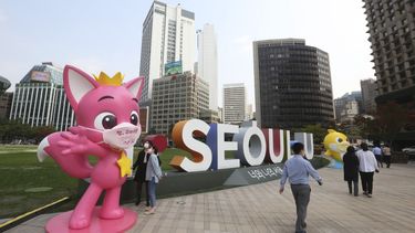 ARCHIVO - Varias personas pasan junto a personajes de Pinkfong, una empresa surcoreana de contenido para niños, durante una campaña de prevención del COVID-19 en la Plaza del Ayuntamiento en Seúl, el 12 de octubre de 2020. En la mascarilla del personaje pone Muchas gracias. (AP Foto/Ahn Young-joon, archivo)