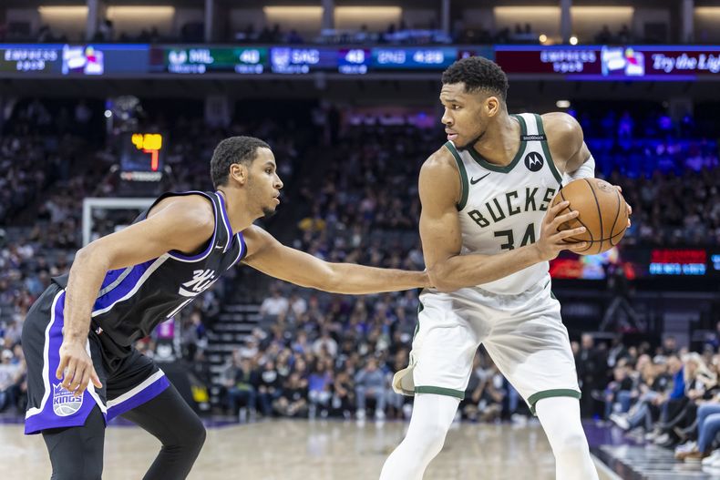 El alero de los Bucks de Milwaukee, Giannis Antetokounmpo (34), busca pasar el balón mientras el alero de los Kings de Sacramento, Keegan Murray, a la izquierda, defiende durante la primera mitad de un partido de baloncesto de la NBA, el sábado 22 de marzo de 2025, en Sacramento, California (AP Foto/Sara Nevis)