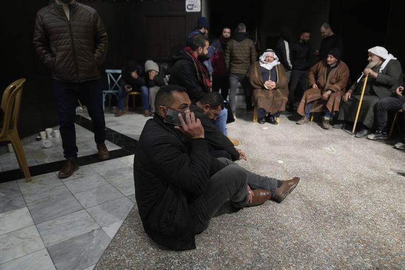 Un hombre espera la liberación de prisioneros palestinos sentado en el suelo mientras utiliza su celular, el domingo 23 de febrero de 2025, tras recibir noticias de que Israel ha retrasado la liberación de cientos de presos palestinos prevista para el sábado, en la ciudad cisjordana de Ramala. (AP Foto/Nasser Nasser)