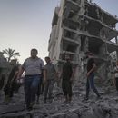 Palestinos caminan sobre los escombros dejados por un bombardeo israelí contra en Deir al Balah, en la Franja de Gaza, el martes 6 de agosto de 2024. (AP Foto/Abdel Kareem Hana)