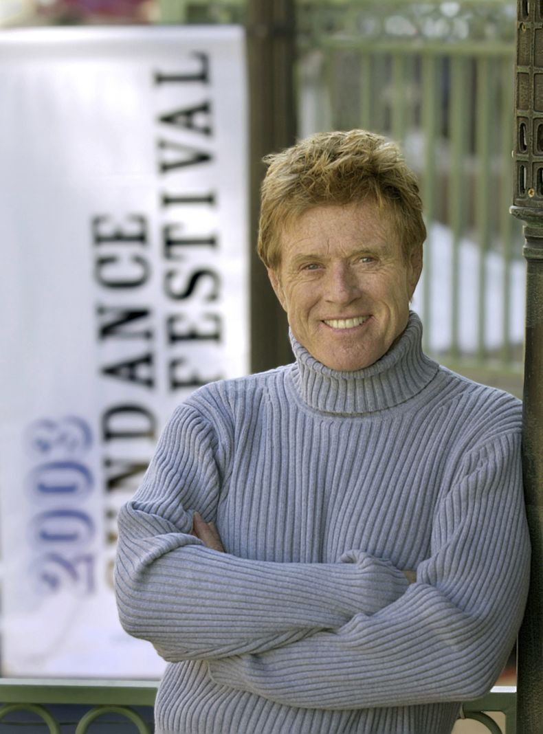 ARCHIVO - Robert Redford posa cerca de una de sus pancartas del Festival de Cine de Sundance el 17 de enero de 2003, en Park City, Utah. (Foto AP/Douglas C. Pizac, archivo)