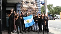 Personal del restaurante Fiorito porta una bandera de Argentina frente a un mural de Lionel Messi en Miami, el miércoles 7 de junio de 2023. (AP Foto/Lynne Sladky)