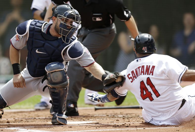 El receptor de los Mellizos de Minnesota Josmil Pinto (izquierda) pone fuera al corredor de los Indios de Cleveland Carlos Santana en el partido del 8 de mayo de 2014. (Foto de AP/Tony Dejak)