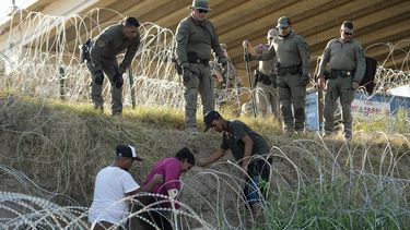 Soldados y guardias de Texas ayudan a una migrante que quedó atrapada en un alambre de púas después de cruzar el Río Grande desde México hacia EEUU, el 1 de agosto de 2023, en Eagle Pass, Texas. (Foto AP/Eric Gay)