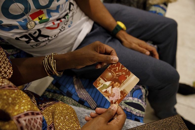 Keachia Bowers sostiene una fotografía de ella con su difunto padre en su casa de Accra, Ghana, el viernes 6 de diciembre de 2024. (AP foto/Misper Apawu)