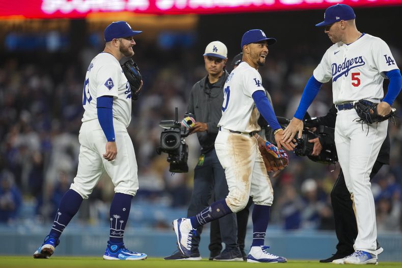 El tercera base de los Dodgers de Los Ángeles, Max Muncy, a la izquierda, el campocorto Mookie Betts, al centro, y el primera base Freddie Freeman (5) celebran después de una victoria por 11-2 sobre los Bravos de Atlanta en el juego de béisbol en Los Ángeles, el sábado 4 de mayo de 2024. (AP Foto/Ashley Landis)