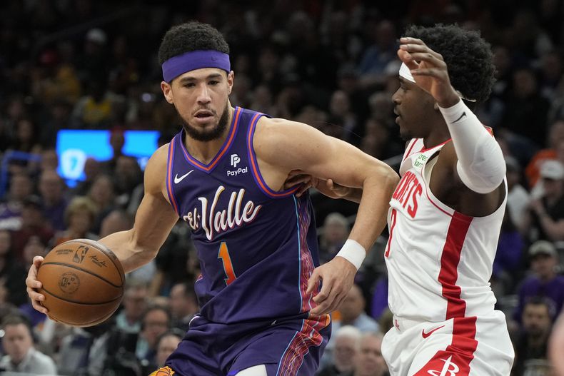 El escolta de los Suns de Phoenix, Devin Booker (1), se enfrenta al escolta de los Rockets de Houston, Aaron Holiday, a la derecha, durante la primera mitad del partido de baloncesto de la NBA, el jueves 29 de febrero de 2024, en Phoenix. (AP Foto/Rick Scuteri)