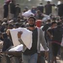 Palestino se reúnen para recibir costales de harina distribuidos por la Agencia de Naciones Unidas para los Refugiados de Palestina en Oriente Próximo (UNRWA), en Deir al Balah, Franja de Gaza, el sábado 2 de noviembre de 2024. (AP Foto/Abdel Kareem Hana)
