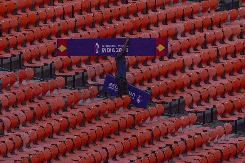 Un trabajador carga un cartel publicitario dentro del estadio Narendra Modi, de cara al Mundial de críquet en Ahmedabad, India, el martes 3 de octubre de 2023 (AP Foto/Rafiq Maqbool)