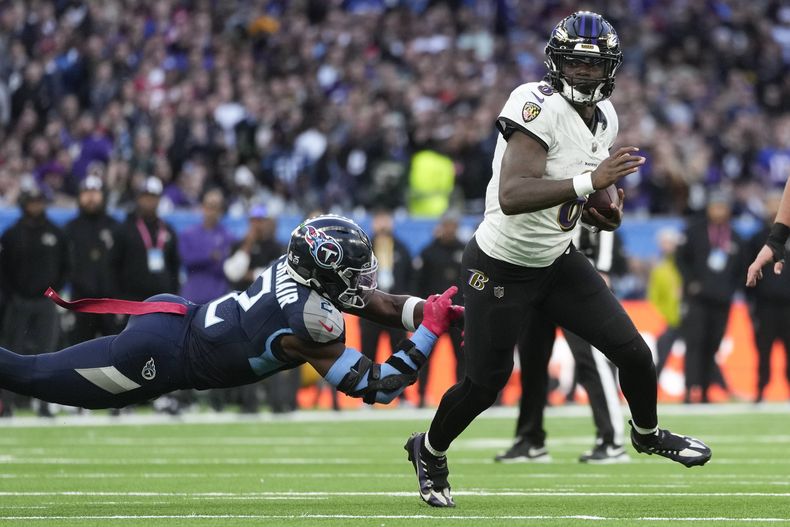 El quarterback de los Ravens Baltimore Lamar Jackson corre con el balón superando al linebacker de los Titans de Tennessee Azeez Al-Shaair en el encuentro en el Estadio del Tottenham del domingo 15 de octubre del 2023. (AP Foto/Kin Cheung)