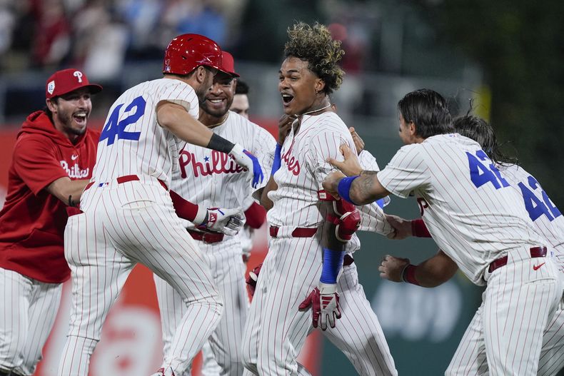 Cristian Pache, centro, de los Filis de Filadelfia, celebra con sus compañeros de equipo después de batear el sencillo productor frente al lanzador de los Rockies de Colorado, Jacob Bird, durante la 10ma entrada del juego de béisbol del lunes 15 de abril de 2024, en Filadelfia. (AP Foto/Matt Rourke)