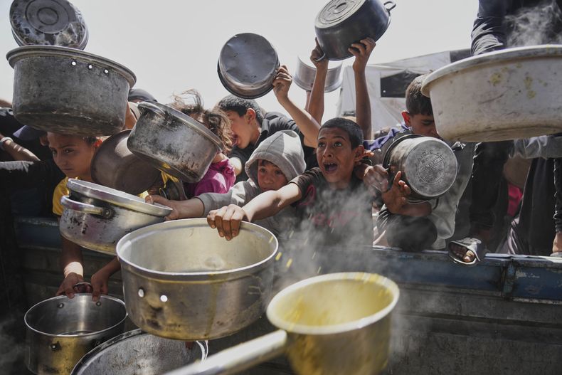 Un niño palestino intenta conseguir comida donada en una cocina comunitaria, el sábado 3 de mayo de 2025, en Jan Yunis, Franja de Gaza. (AP Foto/Abdel Kareem Hana)