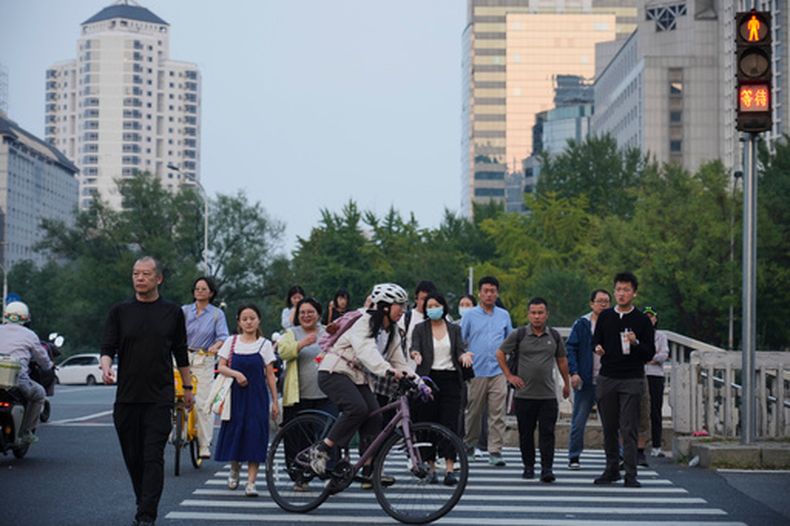 Un grupo de personas cruzan una intersección en Beijing, el lunes 28 de septiembre de 2026. (AP Foto/Achmad Ibrahim)