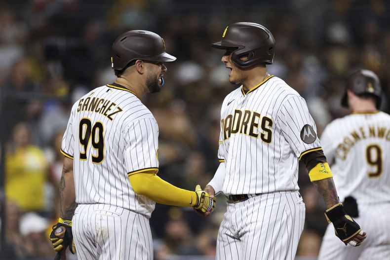 Gary Sánchez, de los Padres de San Diego, felicita a su compatriota dominicano Manny Machado, quien anotó en un doble ante los Guardianes de Cleveland, el martes 13 de junio de 2023 (AP Foto/Derrick Tuskan)