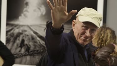 ARCHIVO – El fotógrafo Sebastiao Salgado saluda a fotógrafos en la presentación de su muestra “Kuwait: Un desierto en llamas”, en la Galleria Meravigli, en Milán, Italia, el 20 de octubre de 2017. Salgado, conocido por sus proyectos a largo plazo e imágenes de la naturaleza y la humanidad, falleció a los 81 años, confirmó el Instituto Terra el viernes 23 de mayo de 2025. (AP Foto/Luca Bruno, Archivo)