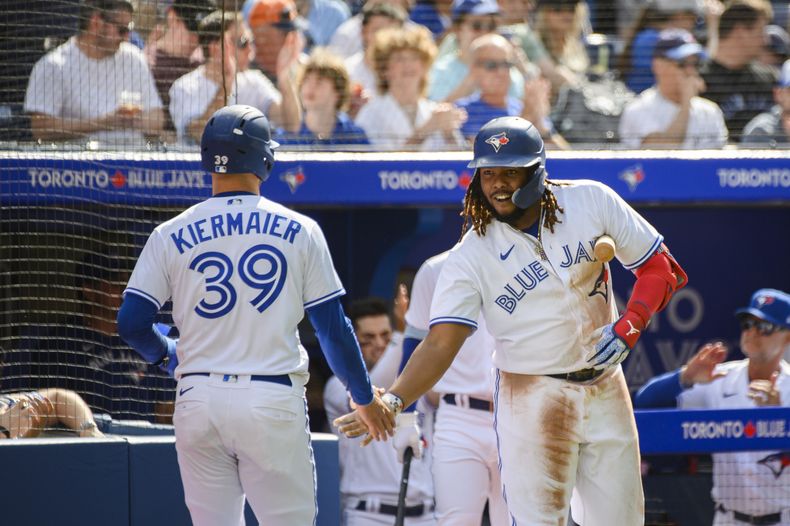 El dominicano Vladimir Guerrero Jr. (derecha), de los Azulejos de Toronto, festeja con su compañero Kevin Kiermaier, quien anotó ante los Bravos de Atlanta el sábado 13 de mayo de 2023 (Christopher Katsarov/The Canadian Press via AP)