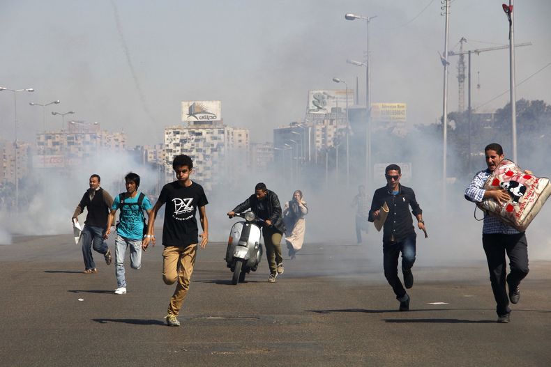 Egipcios huyen de los gases lacrim&oacute;genos tras los enfrentamientos entre los estudiantes de Al-Azhar y la polic&iacute;a durante una protesta en Ciudad Nasr, en El Cairo, el domingo 20 de octubre del 2013. (Foto AP/Heba el-Kholy, Diario El Shorouk)