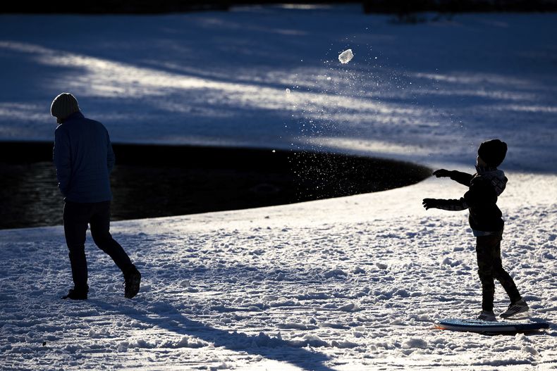 Un niño le arroja una bola de nieve a su papá en Hampton Park tras el paso de una tormenta invernal, el miércoles 22 de enero de 2025, en Charleston, Carolina del Sur. (AP Foto/Mic Smith)