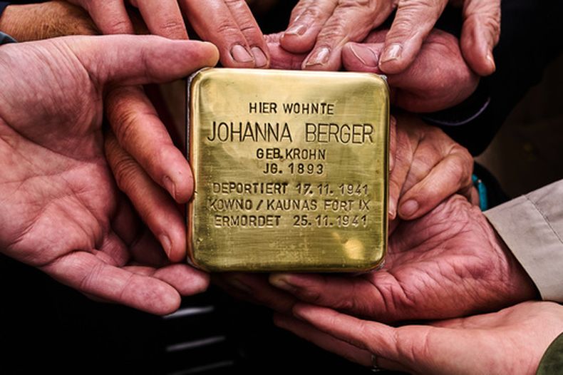 Familiares sujetan el bloque que dice en alemán Johanna Berger, nacida en 1893, vivió aquí. Fue deportada el 17 de noviembre de 1941, asesinada el 25 de noviembre de 1941 en Kowno/Kaunas Fort IX, enfrente de su antigua vivienda en Berlín, Alemania, el 6 de mayo del 2026. (AP foto/Markus Schreiber)