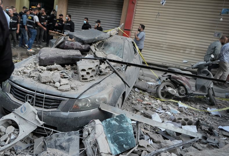 Agentes de seguridad se reúnen cerca de vehículos destruidos en el sitio donde un ataque israelí alcanzara un edificio de departamentos en Dahiyeh, un suburbio en el sur de Beirut, el domingo 23 de noviembre de 2025. (AP Foto/Bilal Hussein)