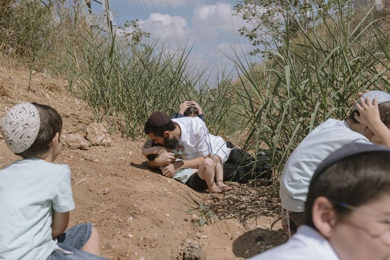 Israelíes se refugian al sonar una sirena que advierte que llegan cohetes disparados desde Gaza, en Rehovot, Israel, viernes 13 de octubre de 2023. (AP Foto/Dor Kedmi)