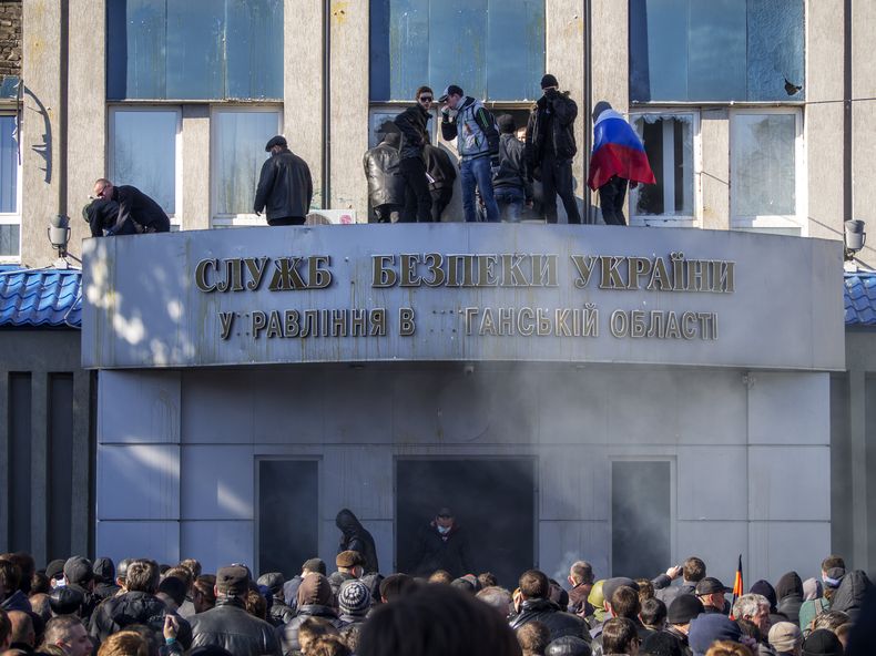 Activistas prorrusos aparecen en el balc&oacute;n de la oficina regional del Servicio de Seguridad en Luhansk, Ucrania, el domingo 6 de abril de 2014. (Foto AP/Igor Golovniov)