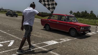 Un Lada rojo cruza la línea de meta para ganar una carrera de resistencia en una antigua pista de aterrizaje sin usar en San Nicolás de Bari, Cuba, el domingo 23 de julio de 2023. (Foto AP/Ramón Espinosa)