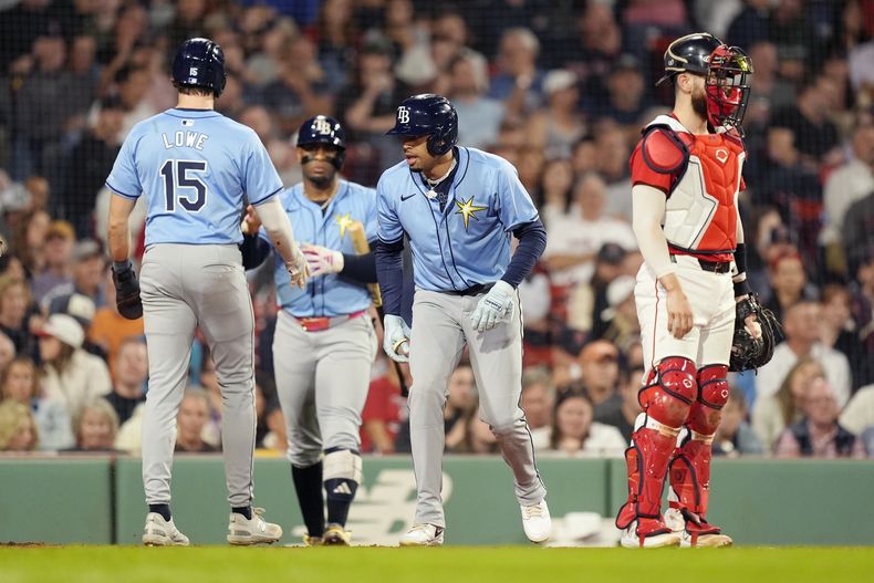 Josh Lowe (15) de los Rays de Tampa Bay anota luego que el dominicano Christopher Morel (centro) ganó una base por bolas con las bases llenas, mientras que el receptor de los Medias Rojas de Boston, Connor Wong mira hacia el frente durante la séptima entrada del juego de béisbol, el viernes 27 de septiembre de 2024, en Boston. (AP Foto/Michael Dwyer)