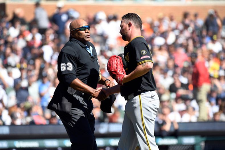 El umpire del plato Laz Diaz le da la mano al abridor de los Piratas de Pittsburgh Kirby Yates tras salir en la segunda entrada ante los Tigres de Detroit el sábado 26 de septiembre del 2026. (AP Foto/Jose Juarez)