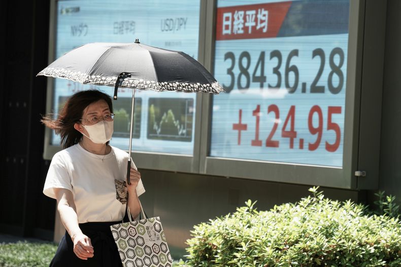 Una persona camina frente a un panel electrónico que muestra el índice Nikkei de Japón en una bolsa de valores el martes 17 de junio de 2025, en Tokio. (AP Foto/Eugene Hoshiko)
