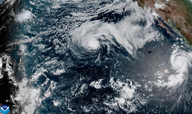 Esta imagen por satélite de NOAA muestra el huracán Fausto, en el centro, y el huracán Genevieve ante la costa surroreste de México, a la derecha, en el océano Pacífico, el domingo 26 de julio de 2026. (NOAA via AP)